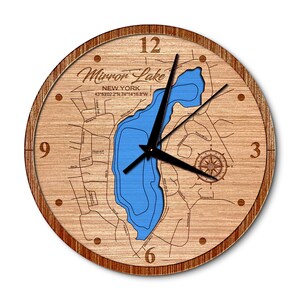 May include: A wooden clock with a map of Mirror Lake, New York. The lake is outlined in blue and the clock face has Roman numerals. The clock is 12 inches in diameter.