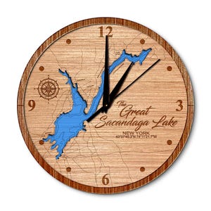 May include: A wooden clock with a map of the Great Sacandaga Lake in New York. The clock face features the lake's outline, compass, and coordinates: 43°07′45.3″N 74°11'21.7"W.