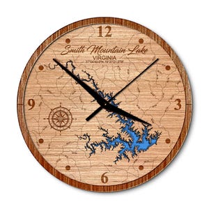 May include: A wooden clock with a map of Smith Mountain Lake, Virginia. The clock face features the lake's outline and surrounding area, with the lake itself highlighted in blue. The clock hands are black, and the numbers are in a simple, classic font.