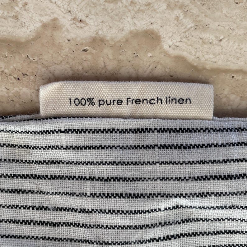 Closeup of the tag on Mellby Atelier linen sleep mask bag, explaining that it's made from 100 % pure French linen.