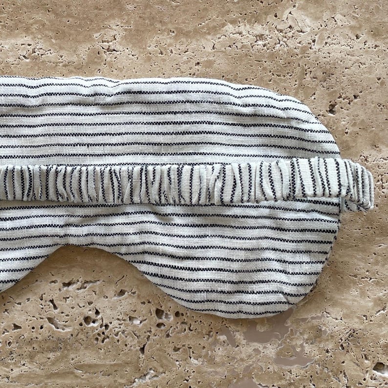 Mellby Atelier linen sleep mask in soft ivory/black pinstripes, closeup of the back showing the soft elastic head band.