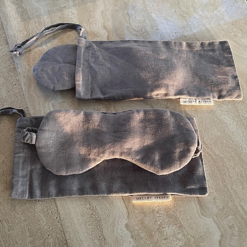 Two Mellby Atelier linen sleep masks with their pouch in charcoal, displayed on a kitchen counter