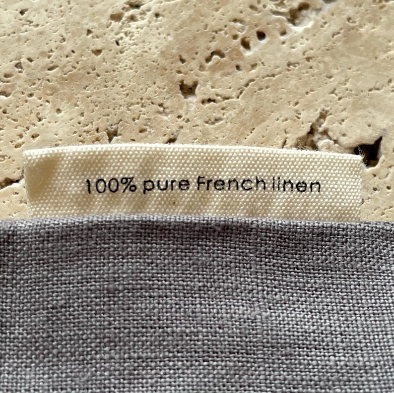 Closeup of the tag on Mellby Atelier linen sleep mask bag, explaining that it's made from 100 % pure French linen.