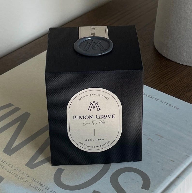 Lemon Grove scented coconut soy candle by Mellby Atelier, packaged in a matte black textured box with front label and wax-sealed closure.