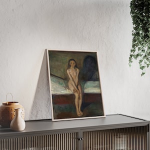 May include: A framed painting of a nude woman sitting on a bed. The woman has long dark hair and is looking at the viewer. The painting is in a muted color palette of browns, greens, and blues.