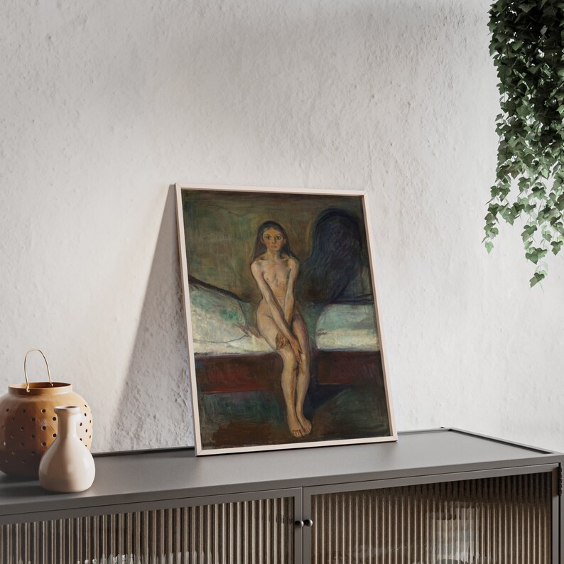 May include: A framed painting of a nude woman sitting on a bed. The woman has long dark hair and is looking at the viewer. The painting is in a muted color palette of browns, greens, and blues.