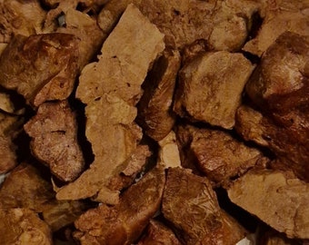 May include: Close-up of a pile of irregularly shaped, brown, and tan pieces. The pieces have a rough, textured surface and vary in size and shape. The lighting creates shadows and highlights, emphasizing the texture and form of the pieces.