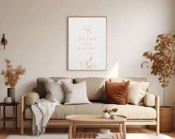 May include: A rectangular wall art print in a wooden frame featuring the text The Lord is my shepherd PSALM 23:1-2 in pink script, accompanied by a pink sun icon and stylized leaf illustrations on a white background, displayed above a beige sofa.