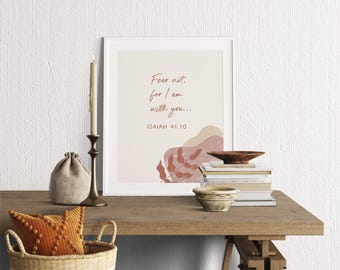 May include: A framed print with the text "Fear not, for I am with you..." and "Isaiah 41:10". The print has a neutral color palette with abstract shapes and is displayed on a wooden table with decorative items.