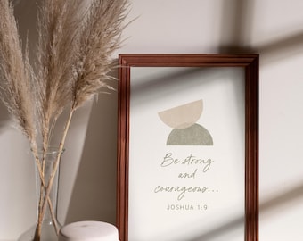 May include: A framed print with the text "Be strong and courageous..." and the reference Joshua 1:9. The print has a brown frame and abstract shapes in neutral colors. A vase with dried plants and a white jar are also in the image.