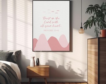 May include: A framed wall art print featuring a white background with pink mountain silhouettes at the bottom. The text reads "Trust in the Lord with all your heart... PROVERBS 3:5-6" in a pink script font, with small pink bird silhouettes above.