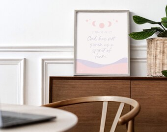May include: A framed wall art print featuring a light pink background with a moon phase graphic, stars, and the text 2 Timothy 1:7, God has not given us a spirit of fear, written in a cursive script above abstract lavender and pink wavy shapes.