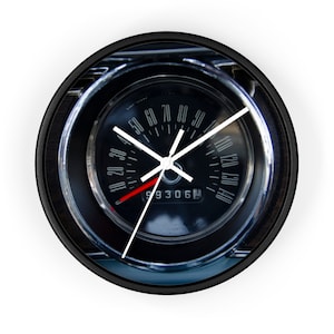 Könnte beinhalten: Runde Wanduhr mit einem Design eines Oldtimer-Tachometers. Das Zifferblatt ist schwarz mit weißen Ziffern und Zeigern sowie einem roten Zeiger. Die Uhr hat einen schwarzen Rahmen und eine Holzmaserung.