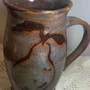 May include: A set of three ceramic mugs with a speckled, matte finish. The mugs are in shades of cream, light gray, and dark gray. Each mug has a simple, minimalist design and a rounded handle. Perfect for coffee or tea.