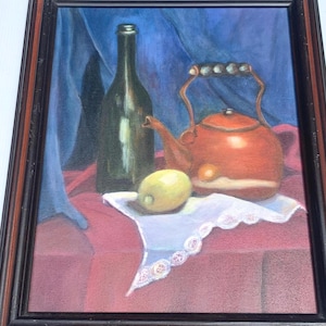 May include: Oil painting of a still life featuring a green bottle, a red teapot, and a lemon on a white cloth. The painting is framed in a dark wood frame, with a blue and red background.
