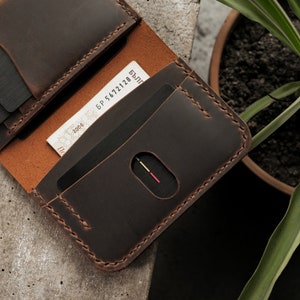 Tobacco brown crazy horse leather card slot detail featuring oval thumb notch for easy card access. Brown waxed thread stitching complements the rich leather color. Surface shows characteristic matte finish with natural grain texture visible.