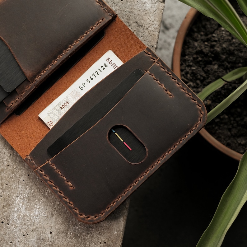 Tobacco brown crazy horse leather card slot detail featuring oval thumb notch for easy card access. Brown waxed thread stitching complements the rich leather color. Surface shows characteristic matte finish with natural grain texture visible.
