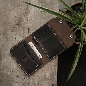 Open wallet view in taupe crazy horse leather showing interior organization with cards and cash positioned in designated slots and compartment. Natural leather lining creates attractive color contrast with darker exterior surface treatment.