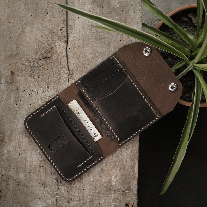 Open wallet view in taupe crazy horse leather showing interior organization with cards and cash positioned in designated slots and compartment. Natural leather lining creates attractive color contrast with darker exterior surface treatment.