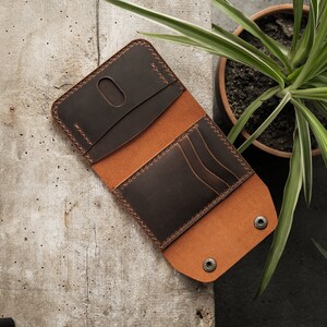 Overhead view of open wallet in tobacco brown crazy horse leather showing complete interior layout from above. Rich brown coloring displays natural leather variation and contrast between exterior surface and lighter edge treatment on flat surface.
