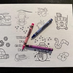 Puede incluir: Un papel blanco con dibujos lineales negros de imágenes con temática invernal, incluyendo un muñeco de nieve, copos de nieve y un iglú. Tres crayones en rosa, azul y morado están sobre el papel. El texto "Winter Fun Color Book" también está presente.