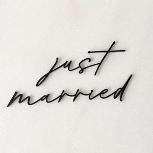 May include: Black cursive text on a white background reads "just married." The words are in a delicate, handwritten style, perfect for wedding decor or announcements. The image is simple and elegant.