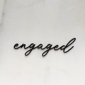 Op de afbeelding: Het woord "Engaged" in een cursief handschrift, geschreven in zwart op een witte achtergrond.