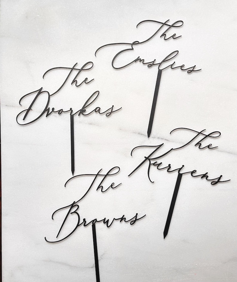 K&ouml;nnte beinhalten: Schwarze, lasergeschnittene Tortenaufs&auml;tze mit den Namen "The Dvoraks", "The Emslies", "The Browns" und "The Kurzens" in eleganter Schrift. Jeder Aufsatz hat einen Stab zum einfachen Einstecken in einen Kuchen. Ideal f&uuml;r Hochzeiten oder Familienfeiern.