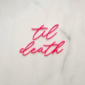 May include: Pink acrylic sign with the words "til death" in a cursive font.