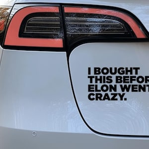 Puede incluir: Un Tesla Model 3 blanco con una pegatina de vinilo negro en el parachoques trasero que dice "Compré esto antes de que Elon se volviera loco."