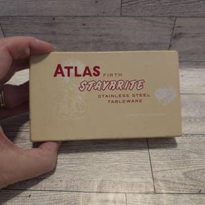 May include: A beige box with the words "ATLAS FIRTH STAYBRITE STAINLESS STEEL TABLEWARE" in red and black lettering. The box has a faded illustration and the words "MADE IN ENGLAND".