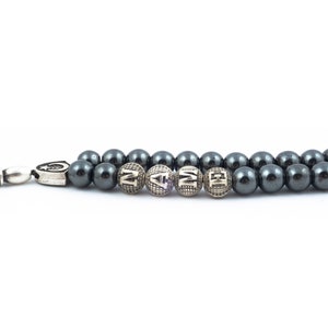 May include: A black beaded bracelet with silver beads that spell out the word "NAME".