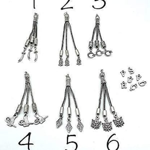 May include: Six different silver tassel charms with various designs, numbered 1 through 6. The charms are for jewelry making or other craft projects.
