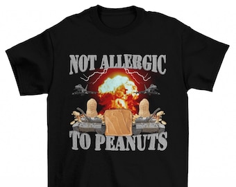 Puede incluir: Camiseta negra con un gráfico de un sándwich de mantequilla de maní frente a una nube en forma de hongo y el texto "No alérgico a los cacahuetes".