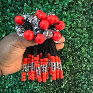 May include: A set of red and clear beads strung on black cords. The beads are arranged in a pattern of alternating red and clear beads. The cords are tied together at the top with a black elastic band.