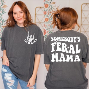 a woman wearing a t - shirt that says somebody's feral mama