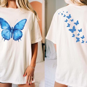 a woman wearing a white shirt with a blue butterfly on it