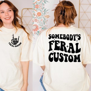 a woman wearing a t - shirt that says somebody's feral custom