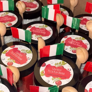 May include: A collection of Casa Bleu Pizza Play Dough jars, each with a label showing tomatoes and the text "Pizza Play Dough." Small Italian flags and wooden spoons are arranged with the jars. The website casableuevents.etsy.com is also visible.