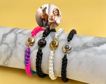 May include: Five different colored braided bracelets with a small round charm in the center of each bracelet. The charms are silver, gold, black, and two different shades of silver.