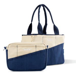 May include: Two-piece set of canvas bags in cream and navy blue. The larger tote bag has handles and the smaller bag has a zipper. Both bags have the word "Sooila" embroidered on them.