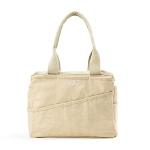 Puede incluir: Una bolsa de lona beige con un logotipo bordado en blanco que dice "Socilla". La bolsa tiene varios bolsillos y una cremallera superior.