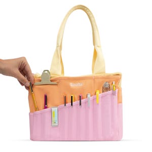 A hand is holding a pencil case with various writing utensils inside, including pens and pencils.