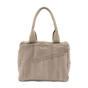 May include: A beige canvas tote bag with the word "Scolia" embroidered on the front. The bag has multiple pockets and a quilted design.