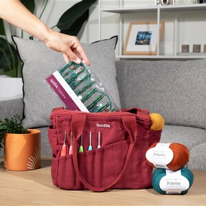 a person is putting items in a red tote bag