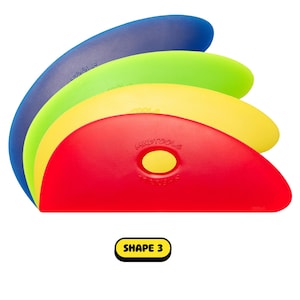 May include: A stack of four colorful Mudtools shape 3 pottery tools. The tools are in shades of blue, green, yellow, and red. The red tool is in the foreground, with the text "MUDTOOLS" and "SHAPE 3" visible.