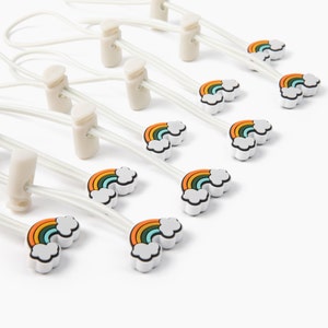 May include: A set of ten white elastic shoelace locks with rainbow cloud designs. Each lock has a white elastic string and a white plastic clip.