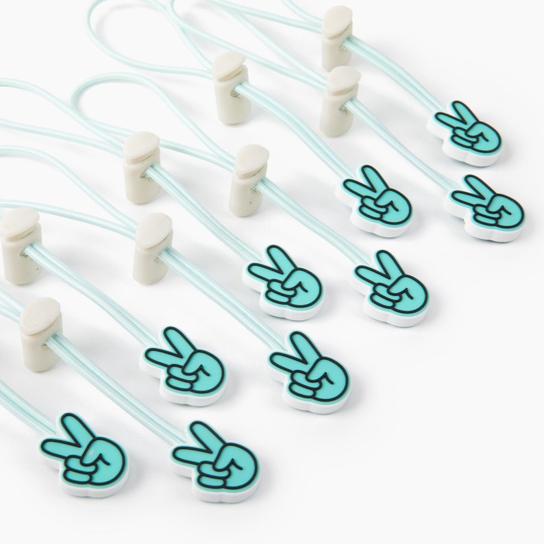 May include: Ten light blue elastic cord toggles with white plastic ends and a peace sign design. Each toggle has a light blue peace sign with a white outline.