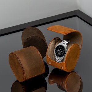 May include: Three brown leather watch boxes, one with a silver watch with a black face inside. The watch has a chronograph function.