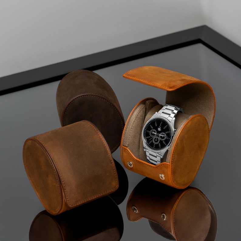 May include: Three brown leather watch boxes, one with a silver watch with a black face inside. The watch has a chronograph function.